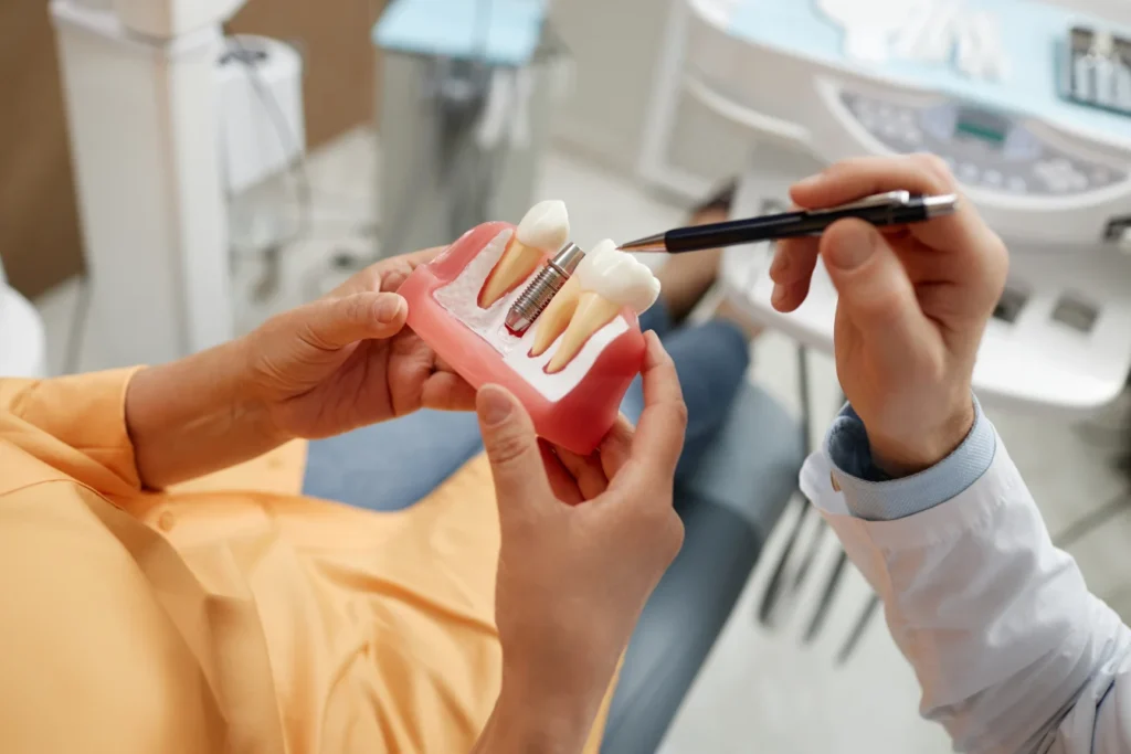 Senior woman holding a model tooth while preparing for dental implant surgery